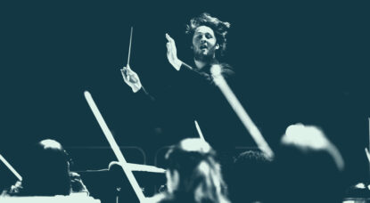 A student conducts energetically in front of an orchestra